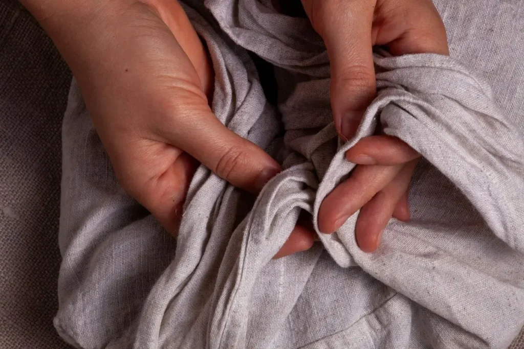 Hands holding linen sheets before washing